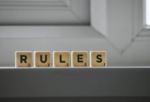 Identical small square shaped cubes with RULES title and numbers on white windowsill near window in house in daylight
