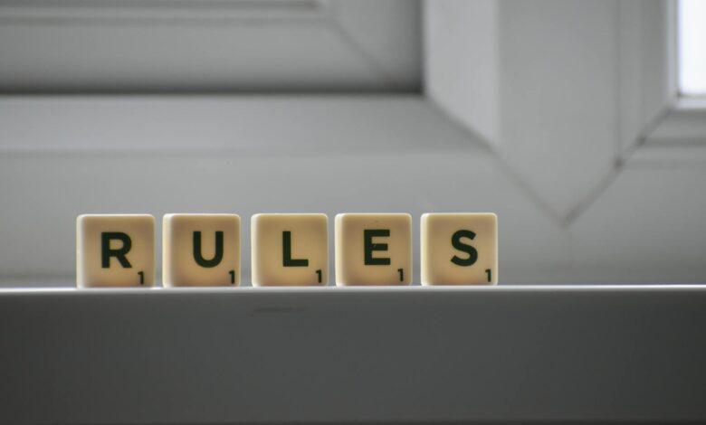 Identical small square shaped cubes with RULES title and numbers on white windowsill near window in house in daylight